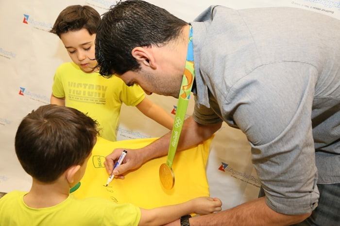A atenção com as crianças autografando camisetas