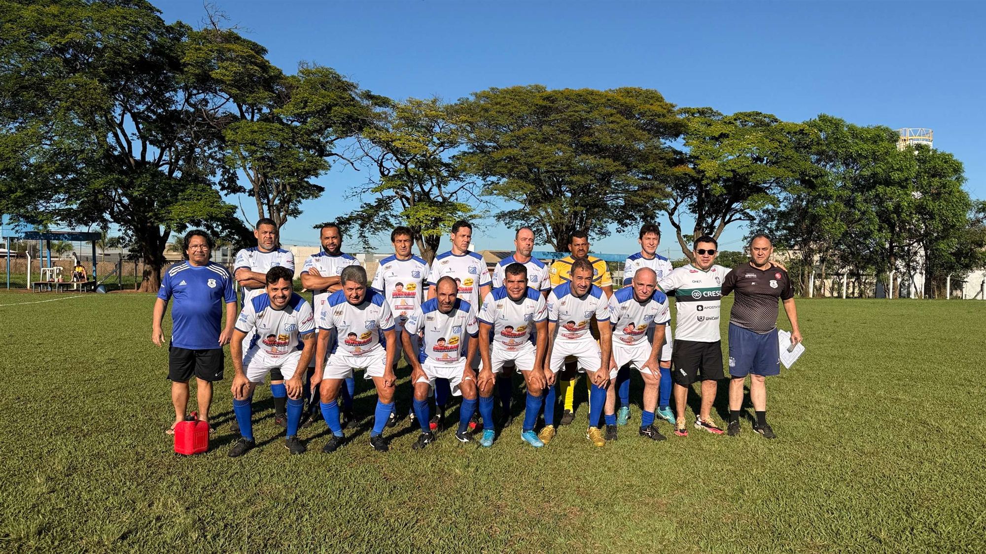 Equipe de camisas brancas e azuis posa para foto no campo antes de jogo do Campeonato Veterano de Futebol de Olímpia