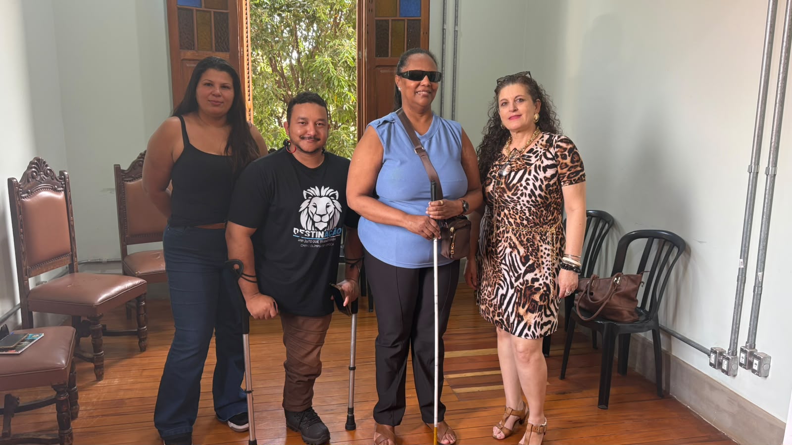 Quatro integrantes do conselho posam juntos em sala com piso de madeira e janela ao fundo