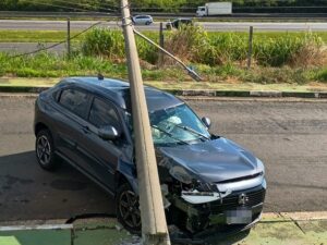 Carro com a frente destruída após bater em poste de concreto, que ficou inclinado sobre o veículo