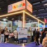 Estande de Olímpia em edição anterior da Feira do Empreendedor, com banner do programa Olímpia Empreendedora e visitantes conversando