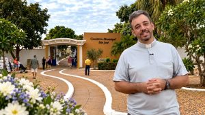 Padre sorri em frente à entrada do Cemitério Municipal São José, em Olímpia