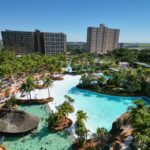 Vista aérea do Hot Beach, em Olímpia, com a praia artificial, piscinas, palmeiras e os prédios dos resorts ao fundo