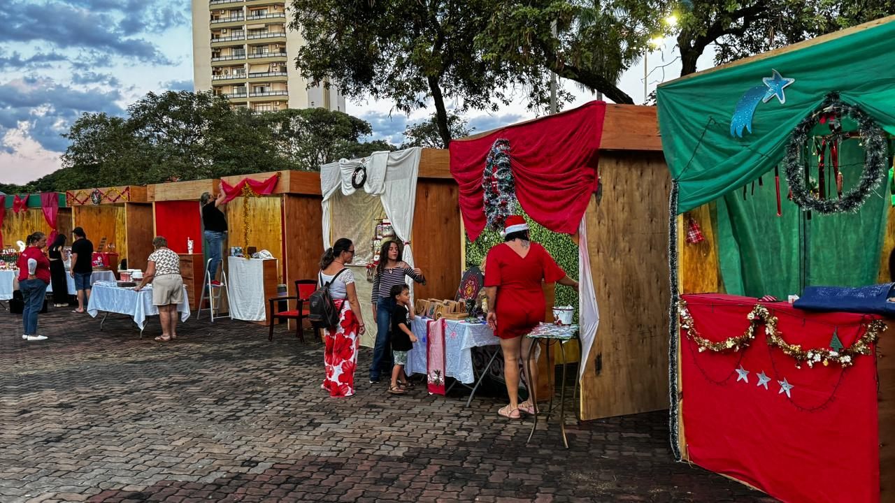 Barracas de madeira com enfeites natalinos e visitantes no Mercado de Natal, em Olímpia