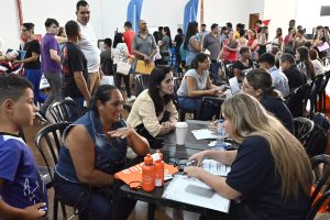 Candidatos conversam com recrutadores em mesas de atendimento, com público ao fundo, durante mutirão de emprego em Olímpia