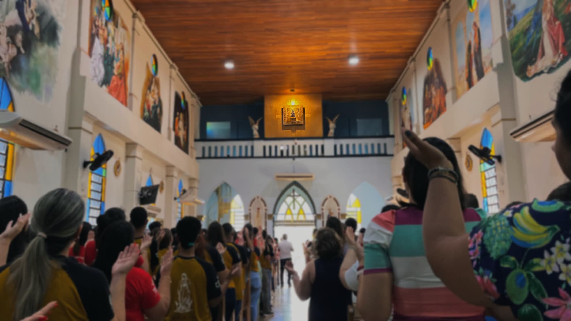 Fiéis com as mãos erguidas na nave do Santuário Nossa Senhora Aparecida, em Olímpia