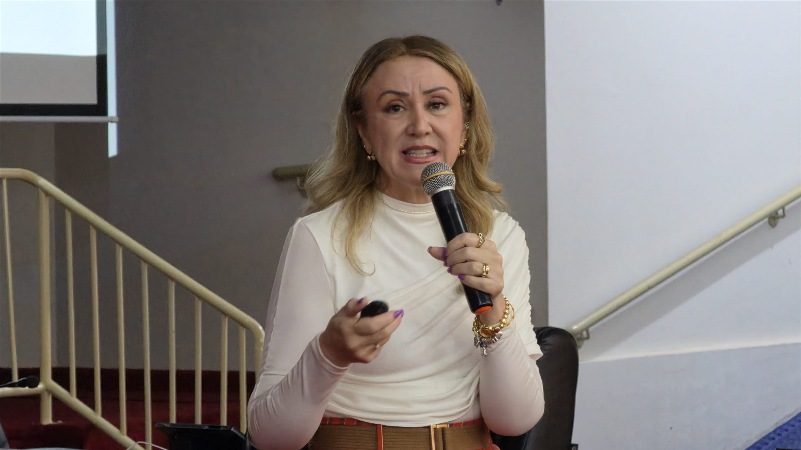 Palestrante gesticula com microfone na mão durante palestra do Outubro Rosa na Câmara de Olímpia