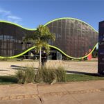 Fachada do Polo Catavento, no Espaço Ruy Ohtake, em Olímpia, com estrutura de curvas contornada por faixa verde e placa de identificação ao lado