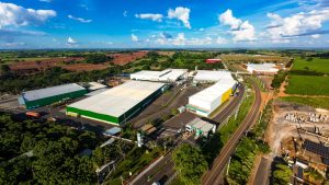 Vista aérea do complexo industrial da Bebidas Poty, em Potirendaba, com galpões brancos e verdes cercados por áreas de lavoura