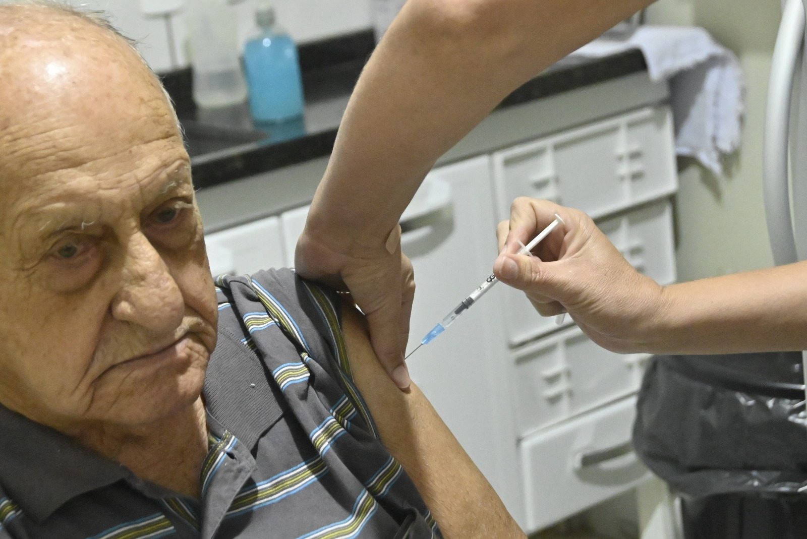 Idoso recebe aplicação de injeção no braço em unidade de saúde de Olímpia