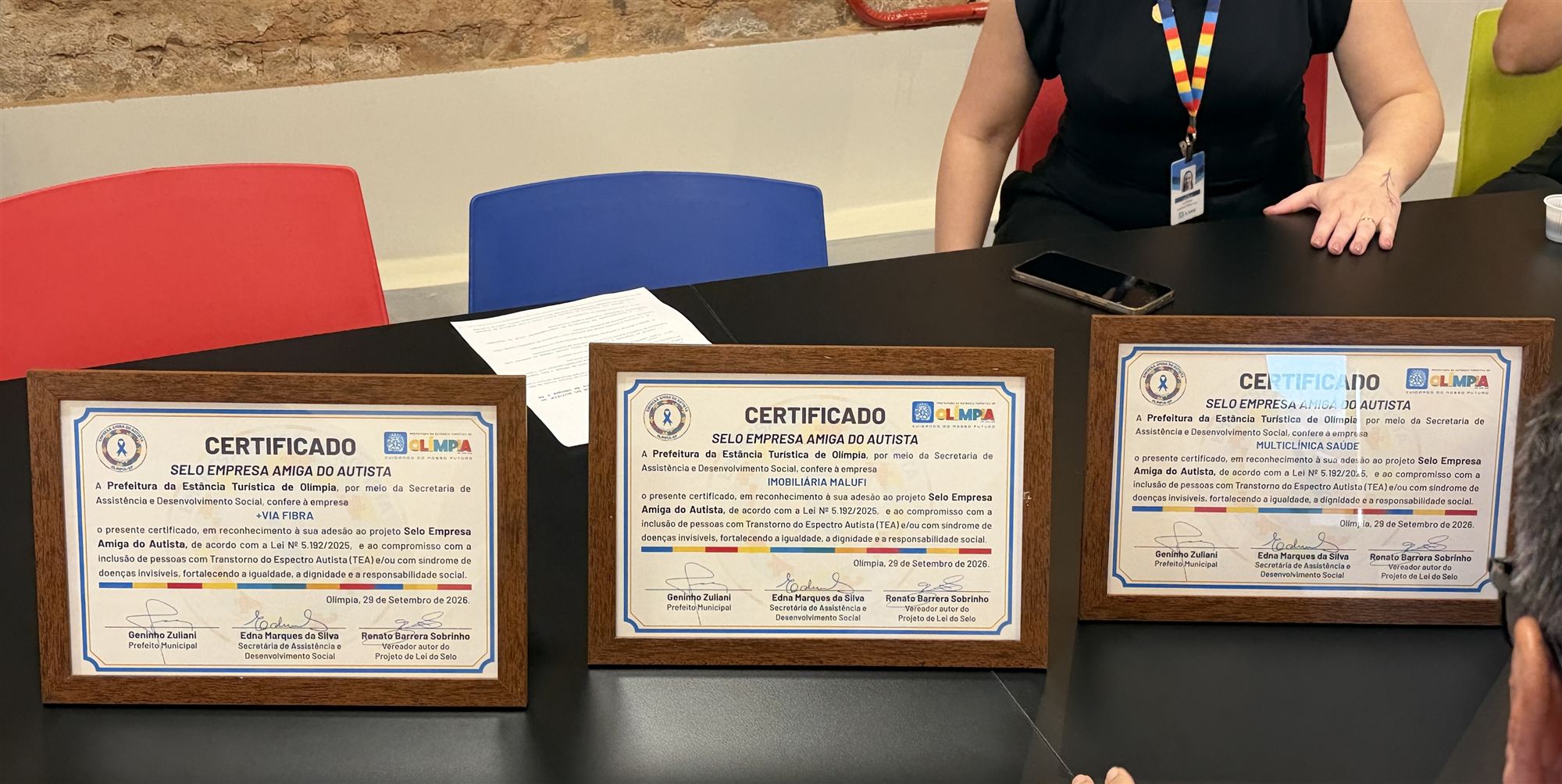Três certificados do selo Empresa Amiga do Autista, das empresas +Via Fibra, Imobiliária Malufi e Multiclínica Saúde, sobre a mesa