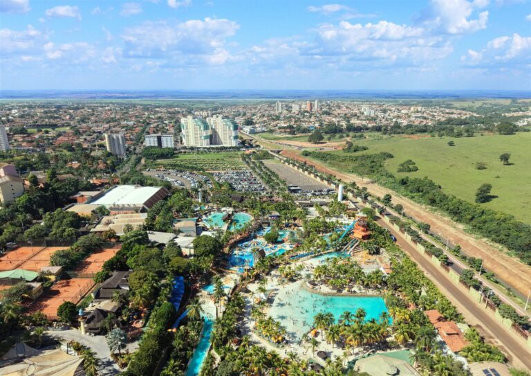 Vista aérea de Olímpia com parque aquático em primeiro plano, prédios ao fundo e área verde ao lado
